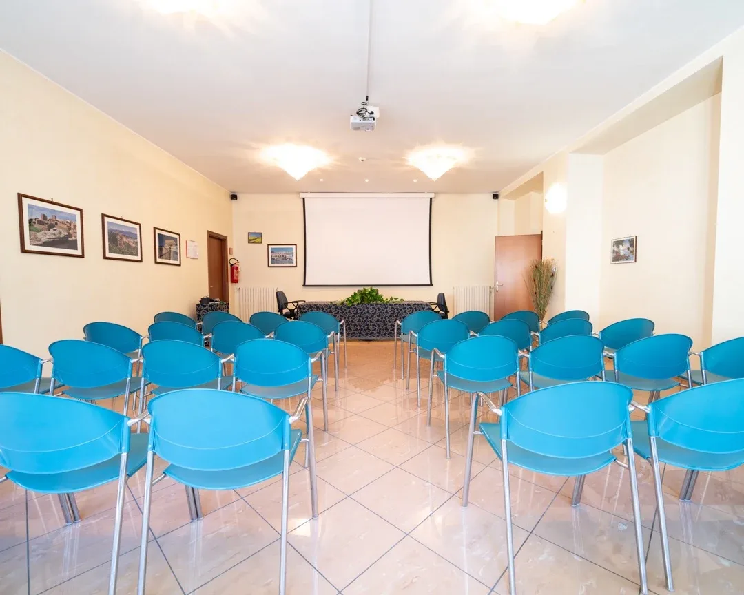 La sala meeting da 110 posti vista dal fondo, con schermo e tavolo relatori