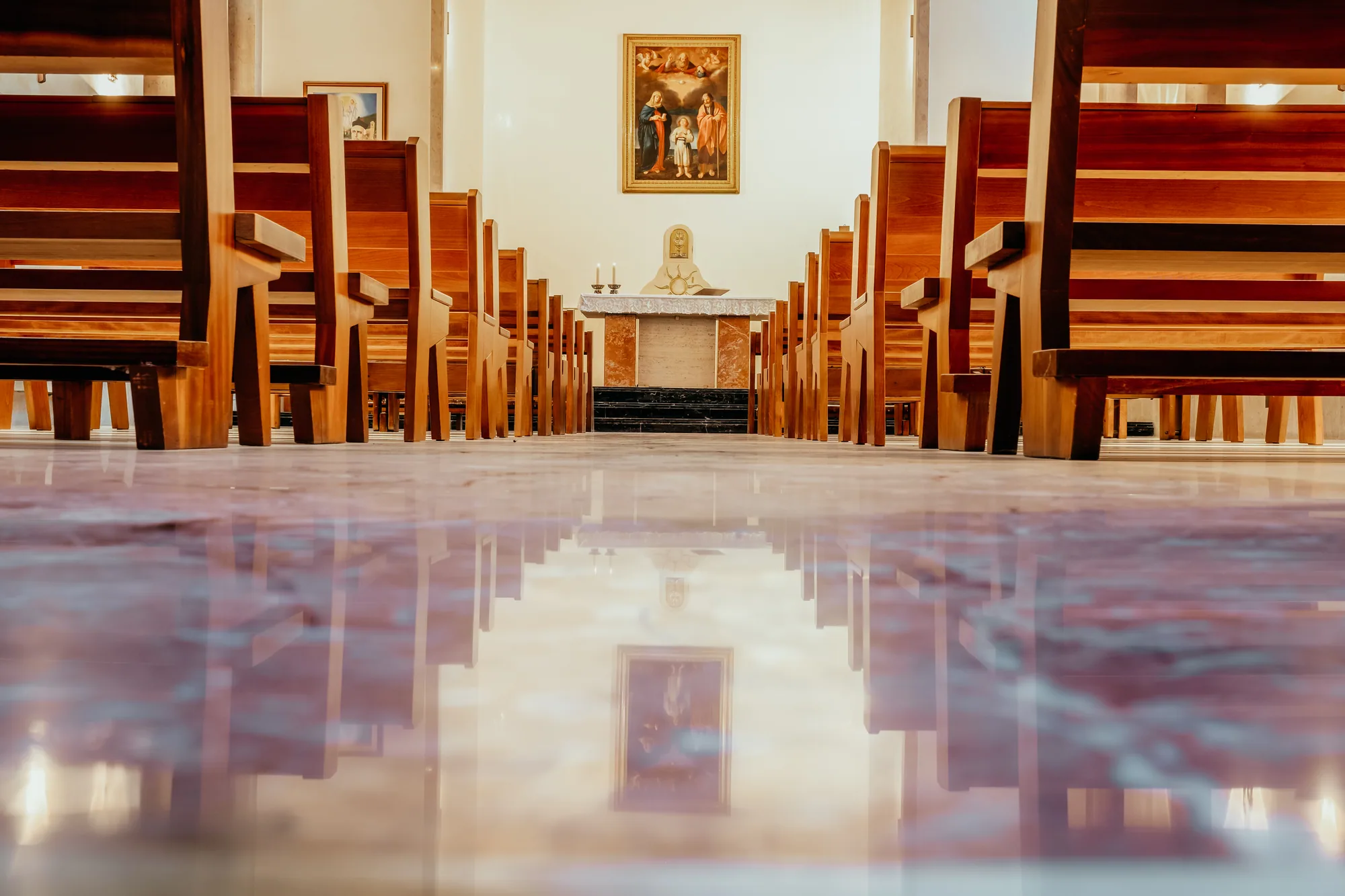 The private chapel at Nazareth Residence, tourist accommodation in the historic centre of Viterbo: wooden pews facing the altar and the Holy Family painting