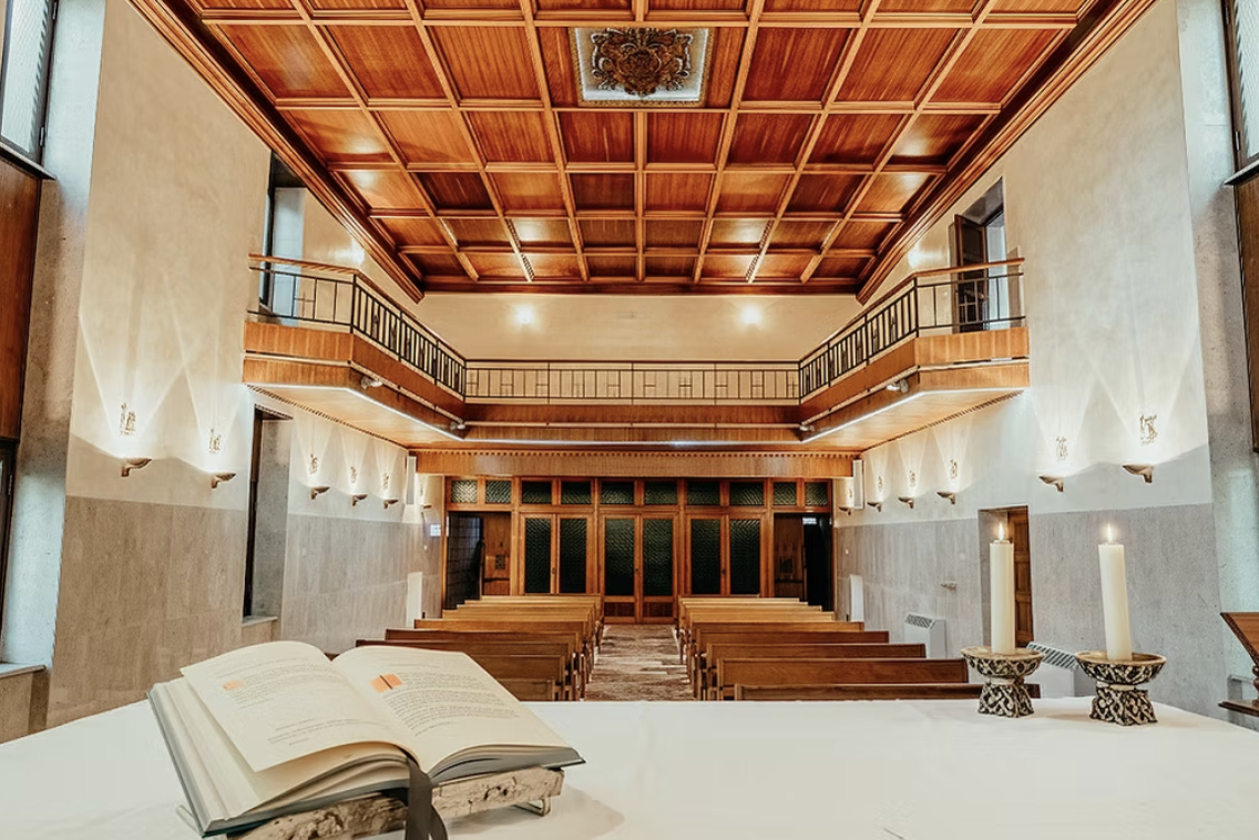 La chiesa interna del Nazareth Residence vista dall'altare, con soffitto a cassettoni in legno e banchi