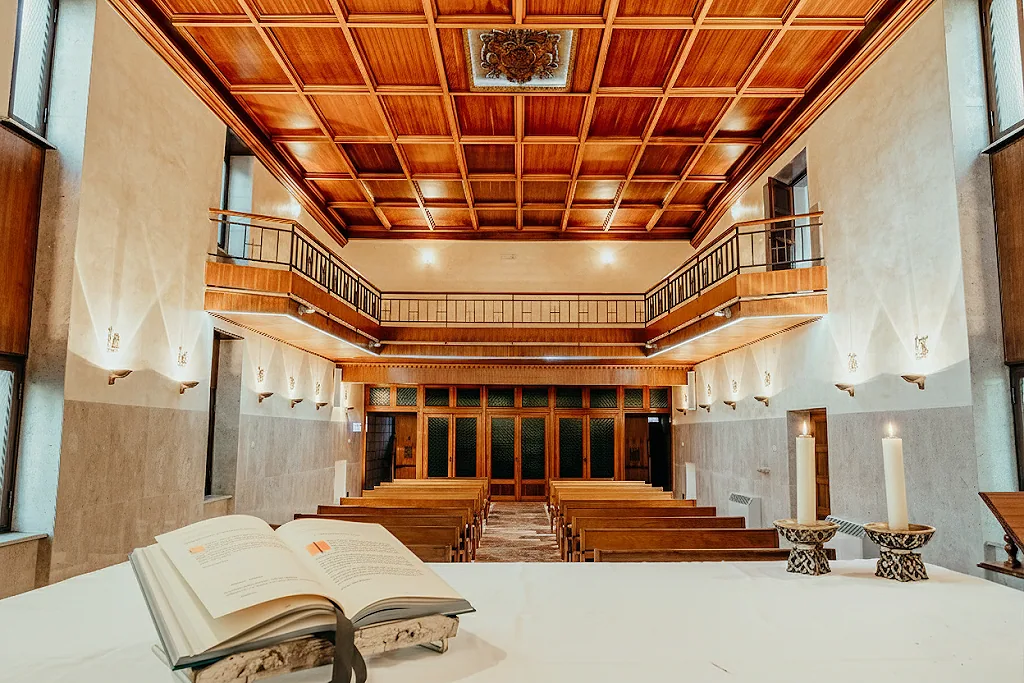 Interno della chiesa verso l'altare, con una Bibbia aperta in primo piano