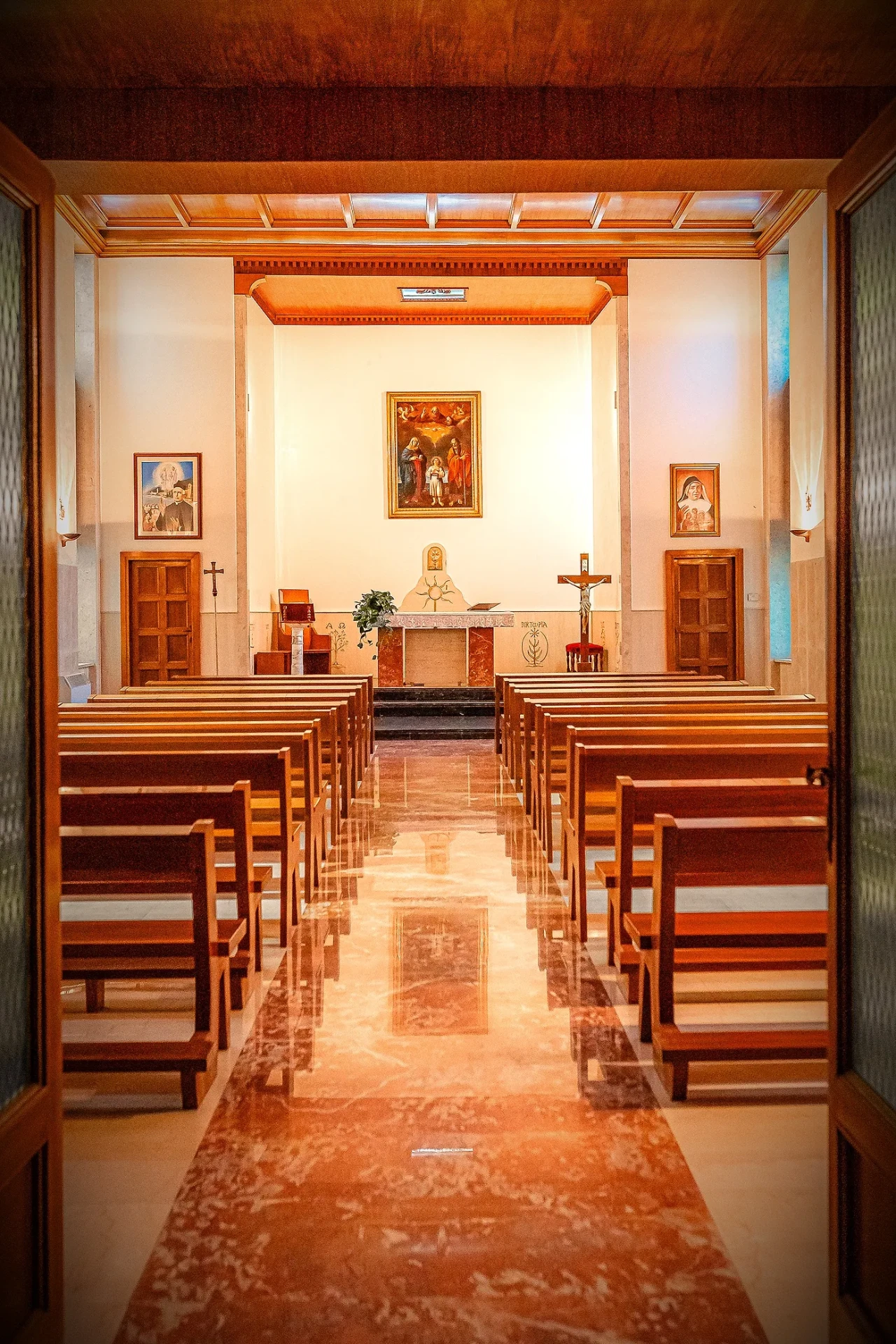 Navata della chiesa interna vista dall'altare, con banchi in legno e pavimento lucido