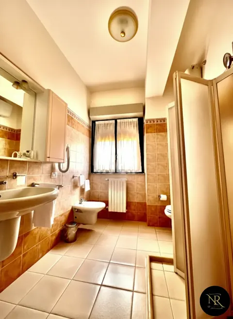 En-suite bathroom in terracotta tones with washbasin, bidet and shower — Nazareth Residence Viterbo