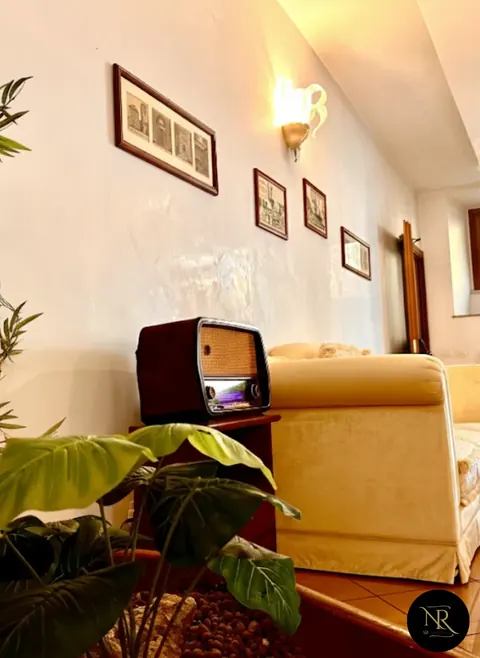 Common lounge with a vintage radio, cream armchair and historic prints of Viterbo