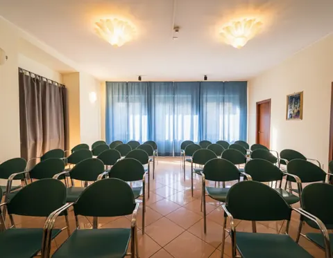Meeting room set up theatre style with green chairs, for events in Viterbo