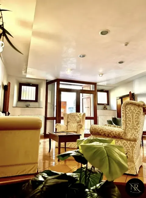 Entrance lounge with ivory damask armchairs and street-facing window, central Viterbo