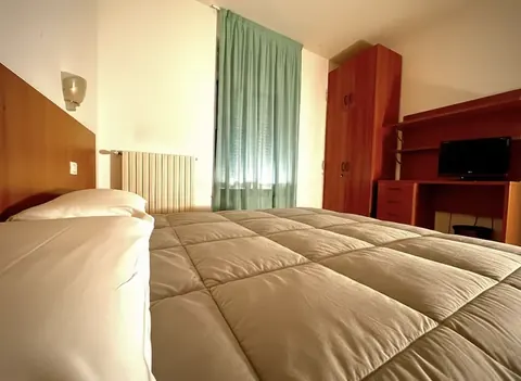 Double room with wooden headboard, cherry wardrobe, TV and desk — historic centre of Viterbo