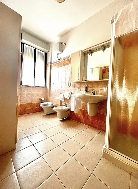 En-suite bathroom with shower, washbasin, toilet and bidet in terracotta tones — rooms in central Viterbo