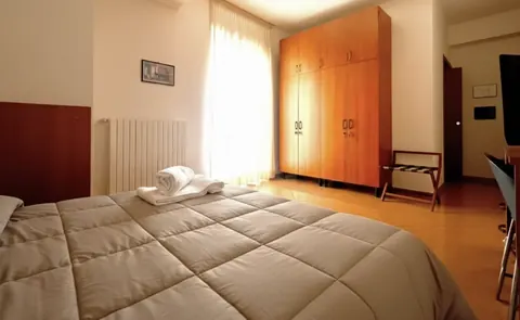 Double room with cherry wardrobe, rolled towels on the bed and TV, central Viterbo