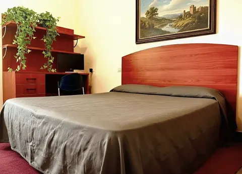 Double room with red wooden headboard, desk and a Tuscia landscape painting